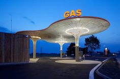 an empty gas station at night with the word gas lit up on it's roof