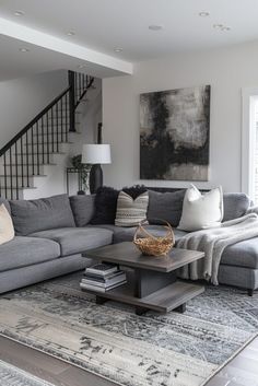 a living room filled with furniture and a stair case next to a large painting on the wall