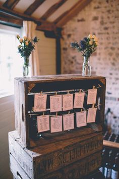 a wooden box with seating cards attached to it and flowers in vases on top