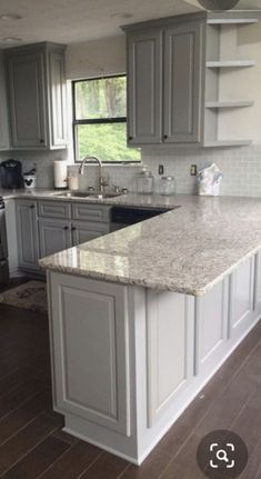 a large kitchen with white cabinets and marble counter tops in the middle of an open floor plan