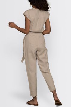 Our Evening Chai Hemp V-Neck Jumpsuit - a chic V-neck ensemble designed for stylish versatility. Featuring micro sleeves and straight-cut legs, this trendy jumpsuit offers a voguish look, perfect from day to night. Crafted with a tapered fit and a concealed placket, this jumpsuit has functional pockets on both sides, adding practicality to its stylish appeal. Elevate your wardrobe with this contemporary piece, ideal for brunch, evening events, or casual outings Wash in cold water or dry clean on Chic Fitted V-neck Pantsuit, Chic Short Sleeve Workwear Pantsuit, Chic Short Sleeve Pantsuit For Work, Casual V-neck Pantsuit For Work, Chic Beige Pantsuit For Summer, Chic Linen Jumpsuits And Rompers With Short Sleeves, Fitted V-neck Pantsuit For Summer, Trendy Jumpsuit, Straight Cut