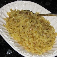 a white plate topped with pasta and meat covered in gravy on top of a table