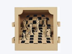 an open cardboard box with chess pieces on the inside and in the outside, as if it were cut out