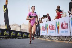 a woman in a pink swimsuit running down a street with other people behind her