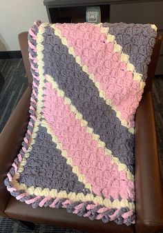 a crocheted blanket sitting on top of a brown chair