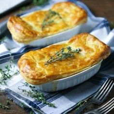 two small pies sitting on top of a blue and white cloth next to silverware