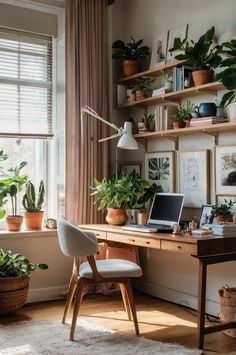 a desk with a laptop on it in front of a window filled with potted plants