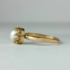 Classic and elegant, this vintage style 14kt gold pearl engagement ring exudes a timeless elegance with a simple band of gold set with a luminous white pearl set within a crown of hearts. Each ring is handmade specifically for you where a hand-wrought slim band of 14kt gold is set with a 6.5-7mm cultured creamy white freshwater pearl in a detailed 14kt gold filigree heart-crown setting. Pearl engagement rings are not only unique, but hold a special meaning as pearls symbolize wisdom, purity, har Classic Yellow Gold Rings With Crown Design, Classic Pearl Ring For Wedding, Classic Wedding Pearl Ring, Classic Crown Ring For Formal Occasions, Elegant Crown Wedding Ring, Elegant Crown Shaped Wedding Rings, Classic Round Rings With Crown Design, Heirloom Pearl Ring Stamped 14k For Wedding, Heirloom 14k Stamped Pearl Ring For Wedding