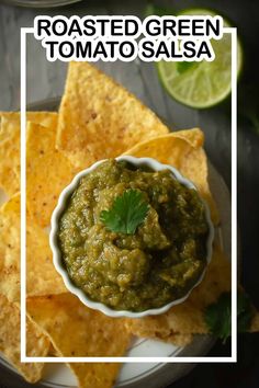 guacamole in a white bowl surrounded by tortilla chips and lime