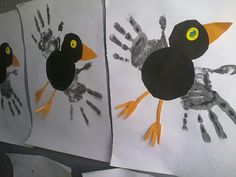 three handprints depicting two birds and one bird with yellow eyes, on white paper