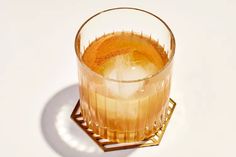 a glass filled with liquid sitting on top of a white table next to a metal stand