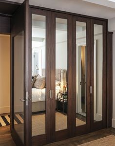 an image of a bedroom with mirrored closet doors in it's center and the door is open