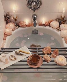 a cup of tea and some rocks in a bathtub with candles on the side