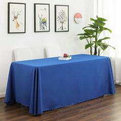 a blue table cloth on top of a wooden table in front of two framed pictures