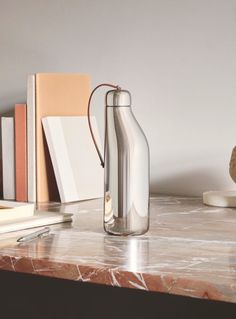 a glass bottle sitting on top of a marble table next to books and a vase