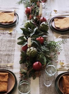 an image of a table setting with apples and greenery on the centerpieces