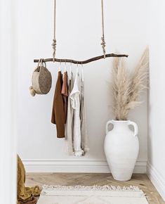 a white vase sitting on top of a wooden floor next to a shelf filled with clothes