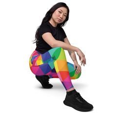 a woman in black shirt and colorful leggings sitting on the ground with her legs crossed