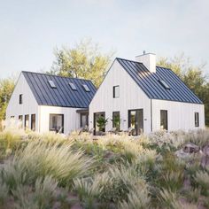 two white houses sitting on top of a grass covered hillside next to trees and bushes