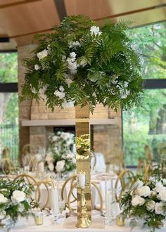 a tall centerpiece with white flowers and greenery sits on top of a table