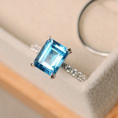 an engagement ring with a blue topazte surrounded by white diamonds in a box