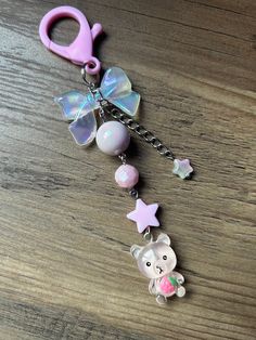 a pink key chain with an elephant and stars attached to it on top of a wooden table