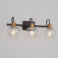 three light bathroom fixture with clear glass globes and brass fittings on the wall