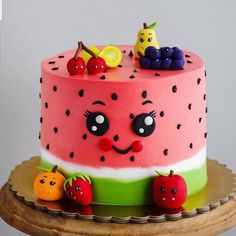 a watermelon cake with fruit on top and faces painted on the side, sitting on a wooden platter