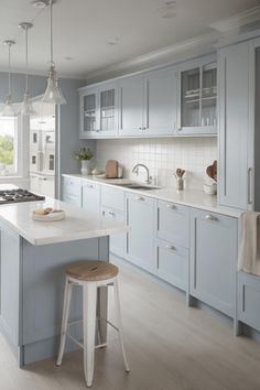 a large kitchen with blue cabinets and white counter tops, along with two stools