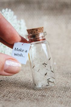 a person is holding a tiny bottle with seeds in it and the label says make a wish