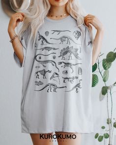 This Unisex t-shirt features a vintage set of dinosaur skeletons and fossils. It is perfect to style with different kinds of alternative fashion like goblincore, grunge, dark academia, & more. Manifest the inner paleontologist in you with this sweatshirt! >> Also available in: - Crewneck --> https://www.etsy.com/listing/1118732683 ABOUT - It is made to order using direct to garment printing. - Runs true to size with a retail fit or size up for an oversized fit. Please refer to size Casual Cotton T-shirt With Dinosaur Print, Unisex Dinosaur Print Crew Neck Top, Graphic Tee With Dinosaur Print For Summer, Dinosaur Print Graphic Tee For Summer, Casual Unisex Dinosaur Print Tops, Cotton Short Sleeve Shirt With Dinosaur Print, Summer Dinosaur Print Graphic Tee, Summer Dinosaur Print Shirt With Crew Neck, Relaxed Fit Dinosaur Print Crew Neck Tops