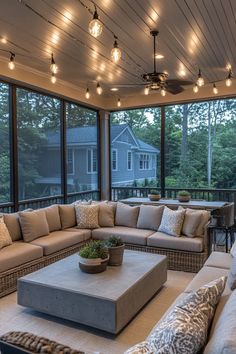 a living room filled with lots of furniture under a covered patio area surrounded by windows