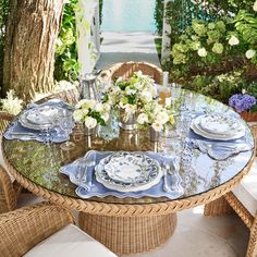 a glass table with plates and flowers on it