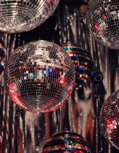 many disco balls hanging from the ceiling in front of a wall with silver sequins