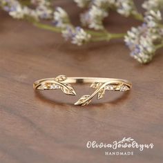 a gold ring with leaves and diamonds on it, sitting next to some lavender flowers