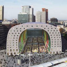 an aerial view of a large building with many people walking around it and buildings in the background