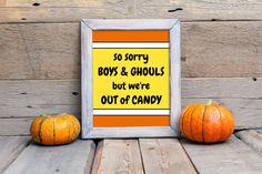 two small pumpkins sitting next to an orange and yellow sign that says, so sorry boys & ghouls but we're out of candy