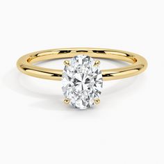 a yellow gold engagement ring with an oval cut diamond in the center, on a white background