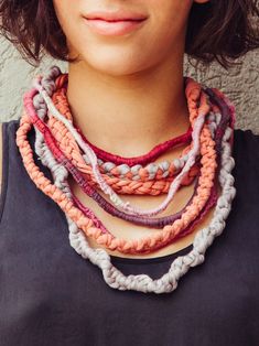 a close up of a person wearing a necklace with multiple strands on it and two beads hanging from the neck