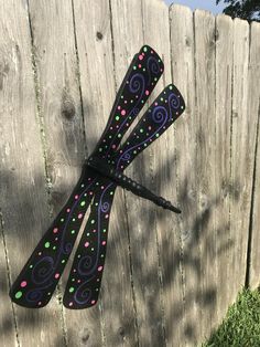 a pair of black and purple scissors on top of a wooden fence