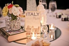 a table topped with books and vases filled with flowers on top of a white table cloth