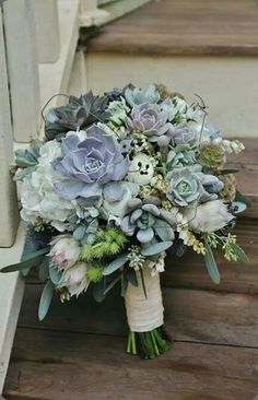 a bouquet of succulents and greenery is sitting on the steps outside