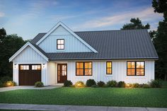 a white house with two garages and lights on the front door is lit up at night