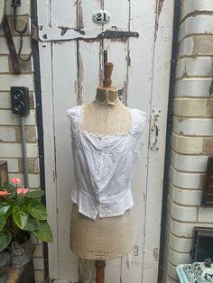 Antique white cotton camisole top corset cover with embroidery and monogram size S/M. 100% Cotton.  Square neck with lace trim, embroidery detail at front and back, monogram, fitted waist. Size:  Chest: 36 inches; Armhole width: 7 inches; Length: shoulder to hem: 20 inches. Weight: allow up to 1 kg once packed. Good condition. Fitted Cotton Lace Tank Top, Fitted Cotton Camisole With Lace Top, Classic Cotton Tank Top For Daywear, Fitted Lace Top Cotton Camisole, White Cotton Tank Top With Square Neck, Classic White Tank Top For Daywear, White Cotton Tank Top With Lace Trim, Fitted Cotton Camisole For Daywear, Cotton Underbust Tops For Summer