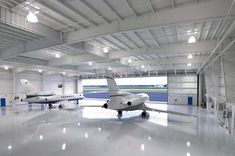 two airplanes are parked in an airplane hanger with lights on the ceiling above them