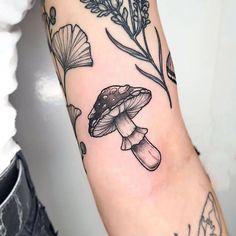 a black and white photo of a mushroom tattoo on the left arm, with flowers in the background