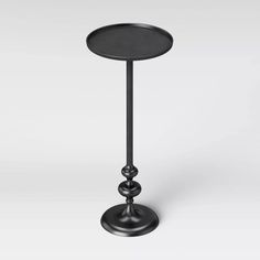 a small black table with a metal base and an iron plate on the top, standing upright against a white background