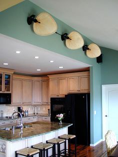 a kitchen with an island and three lights hanging from the ceiling over the stove top