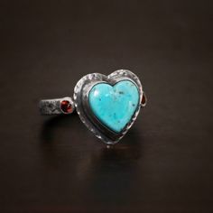 - Sterling Silver - Kingman Turquoise Heart & Garnets - 3mm wide band - Each ring is handmade so will vary slightly Follow Us: Instagram: https://www.instagram.com/wildprairiesilver/ Facebook: https://www.facebook.com/wildprairiesilver/ Visit our Jewelry Website www.wildprairiesilver.com Handmade Jewelry Supplies www.savannahjewelrysupply.com Contact Us: Call or Text: 920-365-6341 Email: info@wildprairiesilver.com Contact Hours: Monday - Friday (8am-4pm central) Bohemian Heart-shaped Anniversary Rings, Handmade Bohemian Heart-shaped Rings, Handmade Heart-shaped Turquoise Ring As Gift, Handmade Turquoise Heart Ring, Turquoise Heart, Jewelry Website, Kingman Turquoise, Wide Bands, Monday Friday