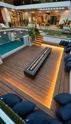 an outdoor deck with blue cushions and lights on the floor next to a swimming pool